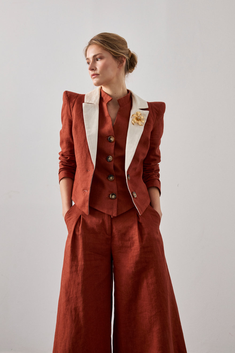 Chaqueta con hombreras en color caldera y solapa a contraste en color crema. Está forrada y se cierra con dos botones en el delantero.