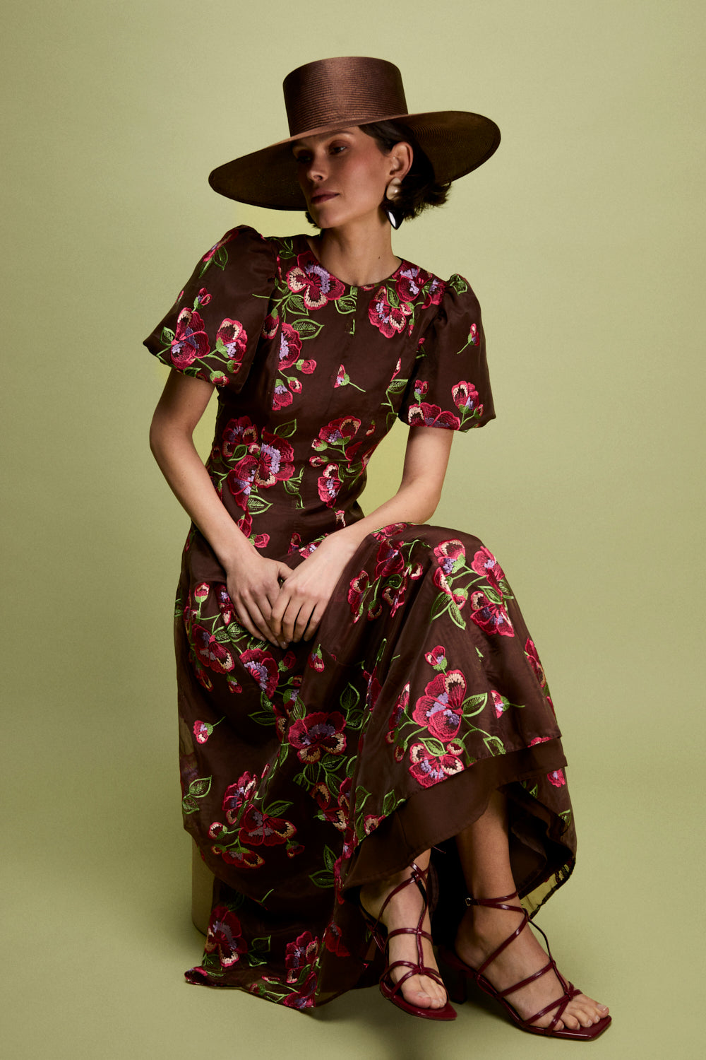 Vestido midi confeccionado en organza marrón con flores bordadas. Tiene cuello a la caja y manga corta abullonada.