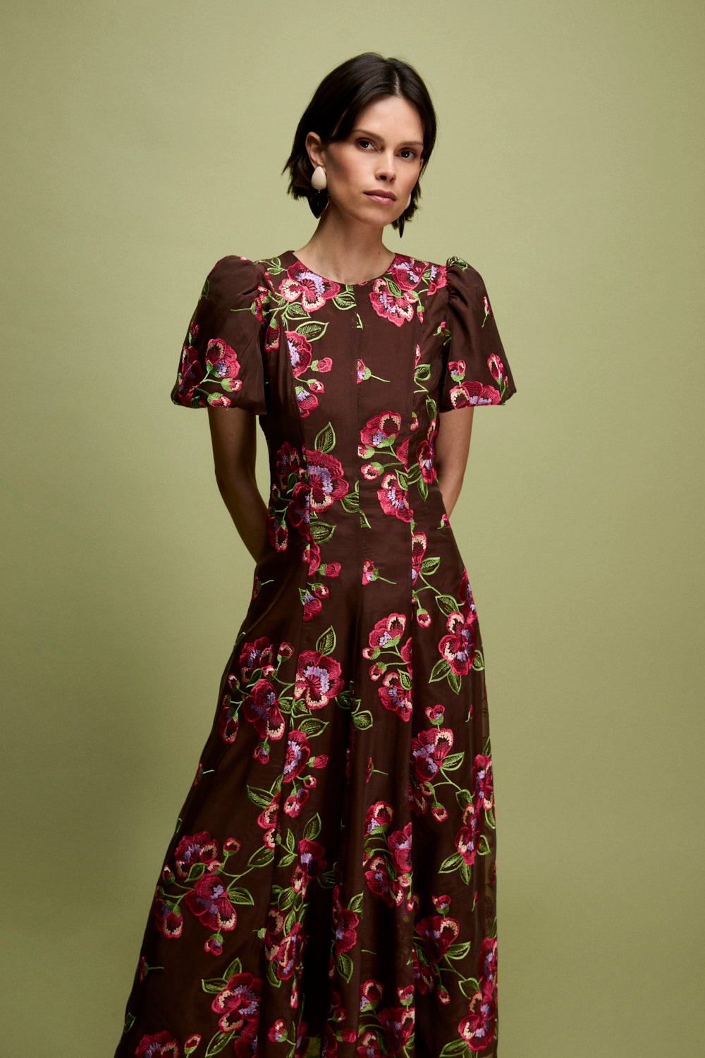 Vestido midi confeccionado en organza marrón con flores bordadas. Tiene cuello a la caja y manga corta abullonada.