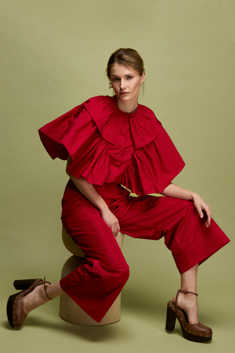 Blusa confeccionada en tafeta en color carmín con frunces y volantes en mangas.