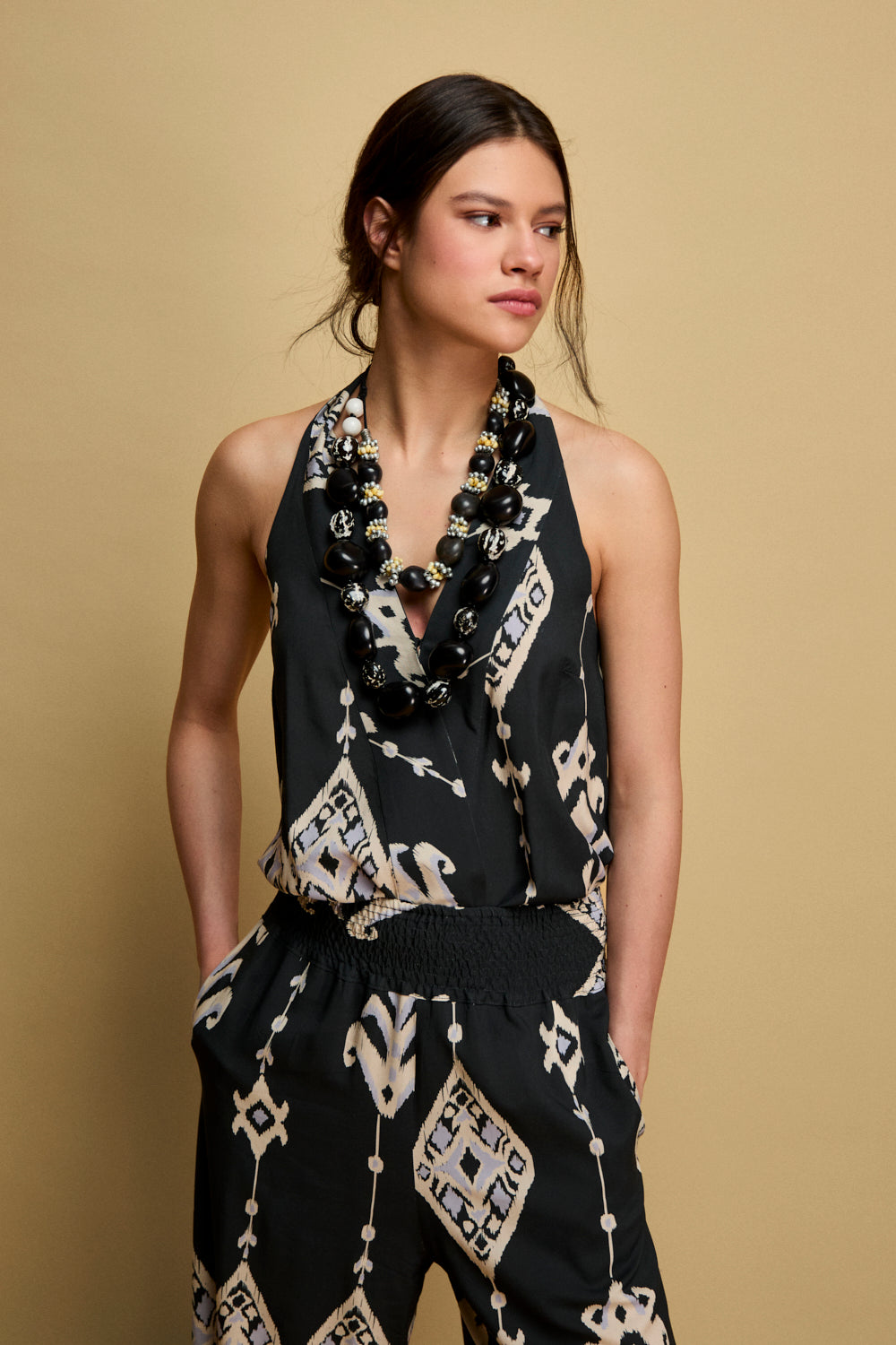 Top sin mangas en color marino con lazada en cuello. Este top tiene corchete en pecho y elástico en espalda.