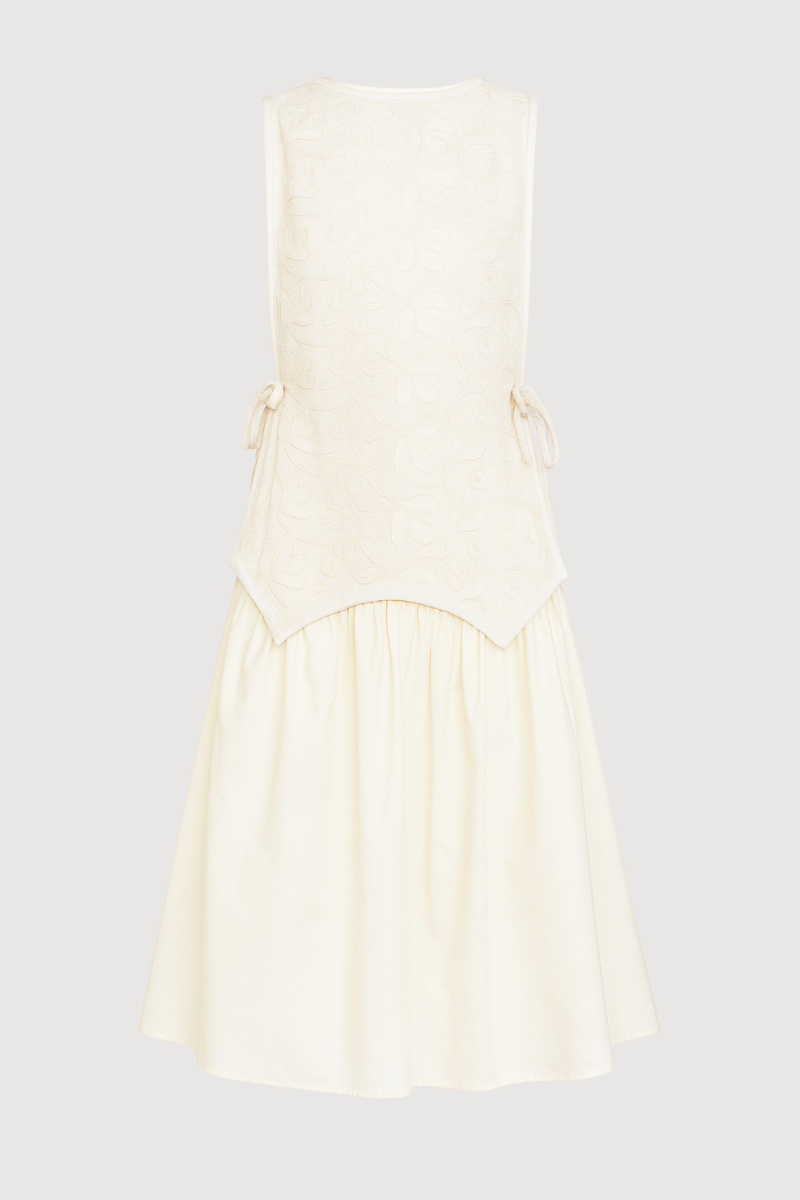 Vestido midi en color crema con top asimetrico de flores bordadas y lazadas en el lateral. 