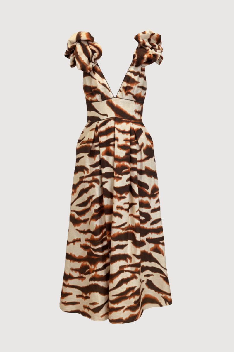 Vestido midi estampado en tonos marrones y teja con escote en V y lazadas en hombros. Este vestido tiene falda tableada con cinturilla e incluye bolsillos.