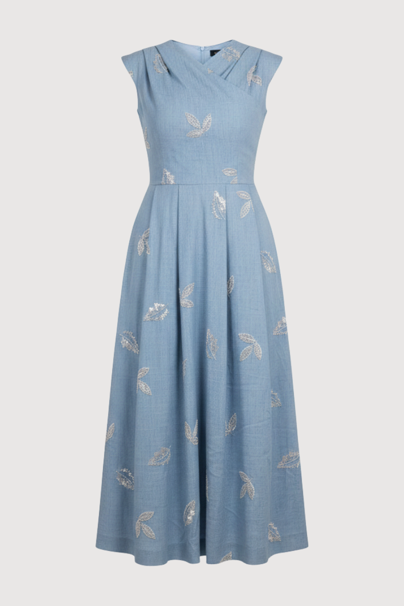 Vestido midi en color celeste con bordados de pailletes. Este vestido tiene pieza fruncida superpuesta en pecho y corte en la cintura. La falda está tableada e incluye bolsillos.