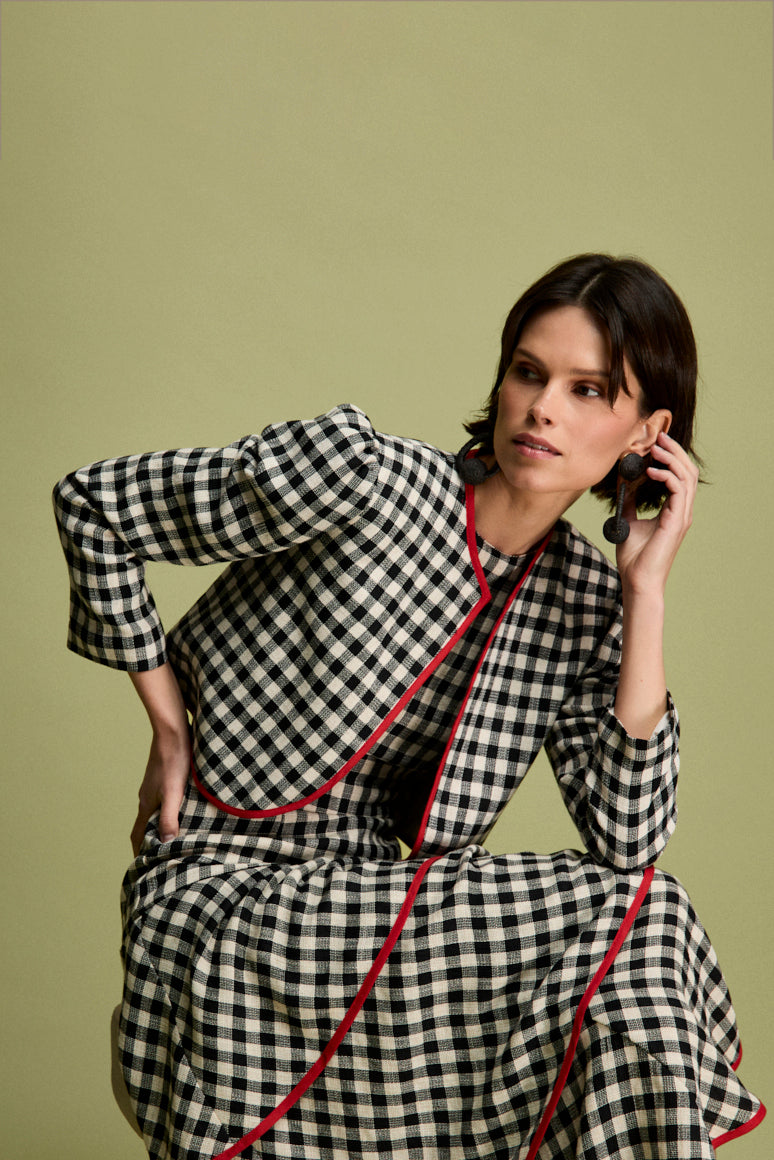 Vestido midi vichy con escote halter y corte en la cintura. La falda está compuesta por volantes viveados en rojo. 